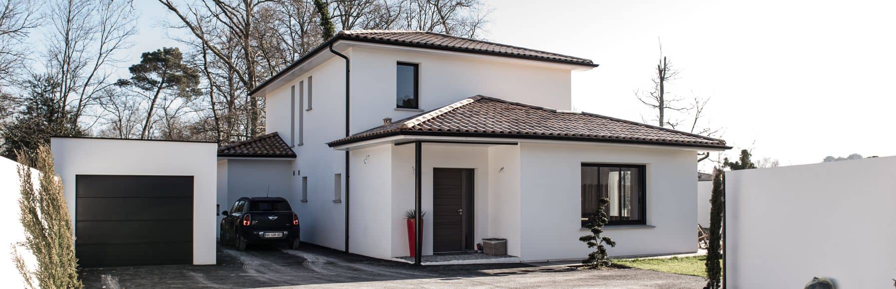 Maison moderne blanche avec garage et jardin, vue extérieure.
